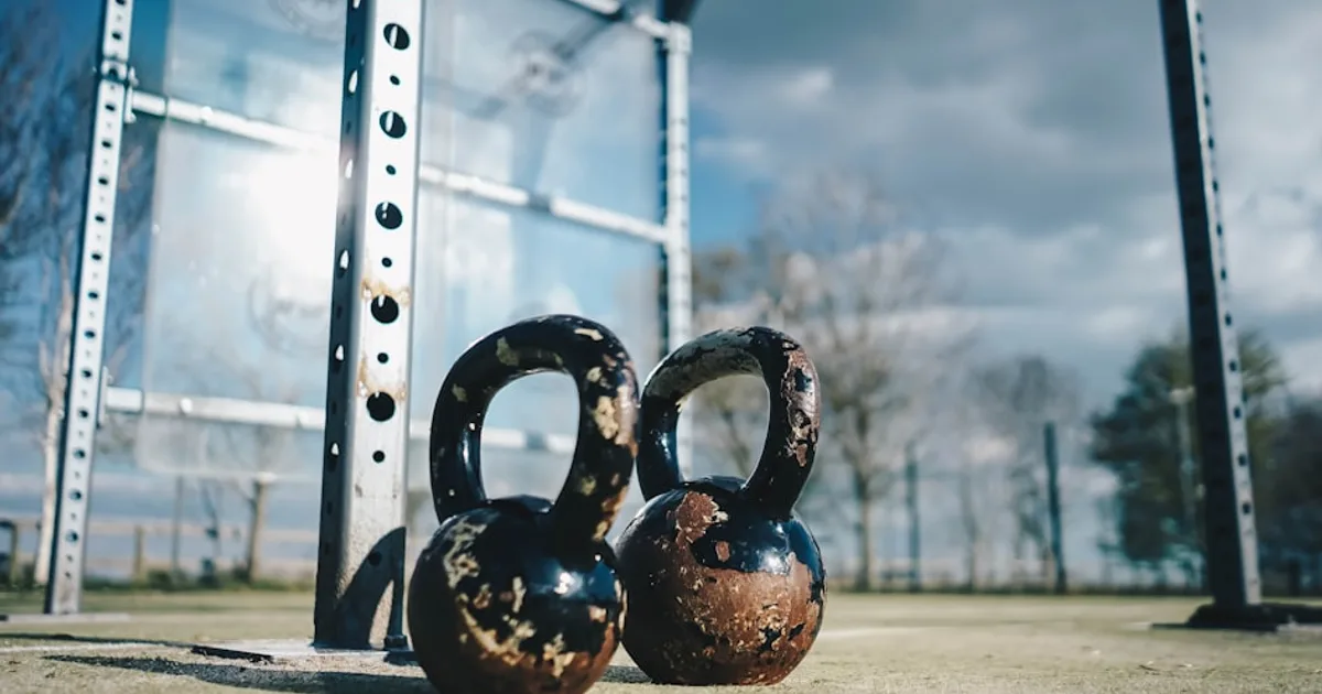 Principiante haciendo CrossFit con kettlebell bajo supervisión de entrenador
